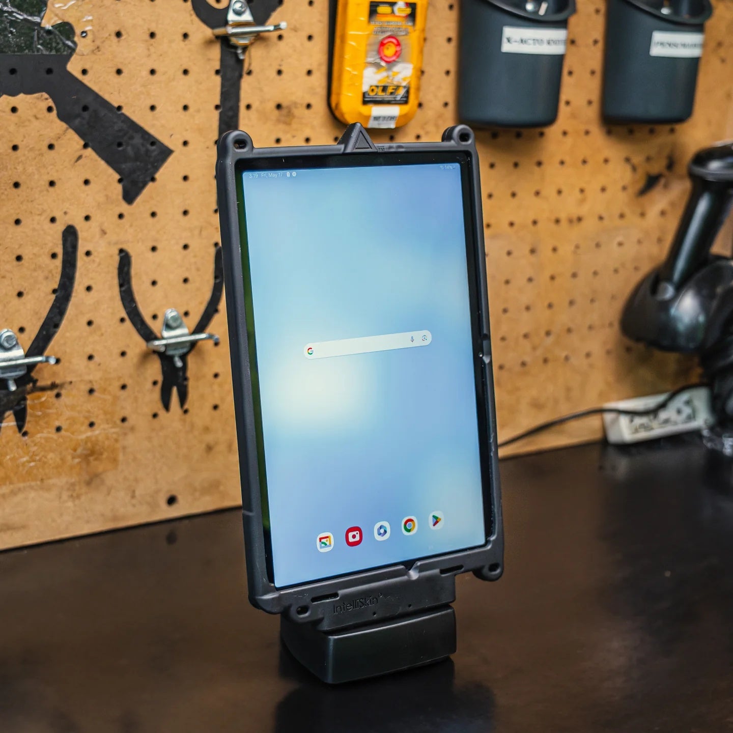 Tablet in portrait orientation on charging dock with a pegboard background