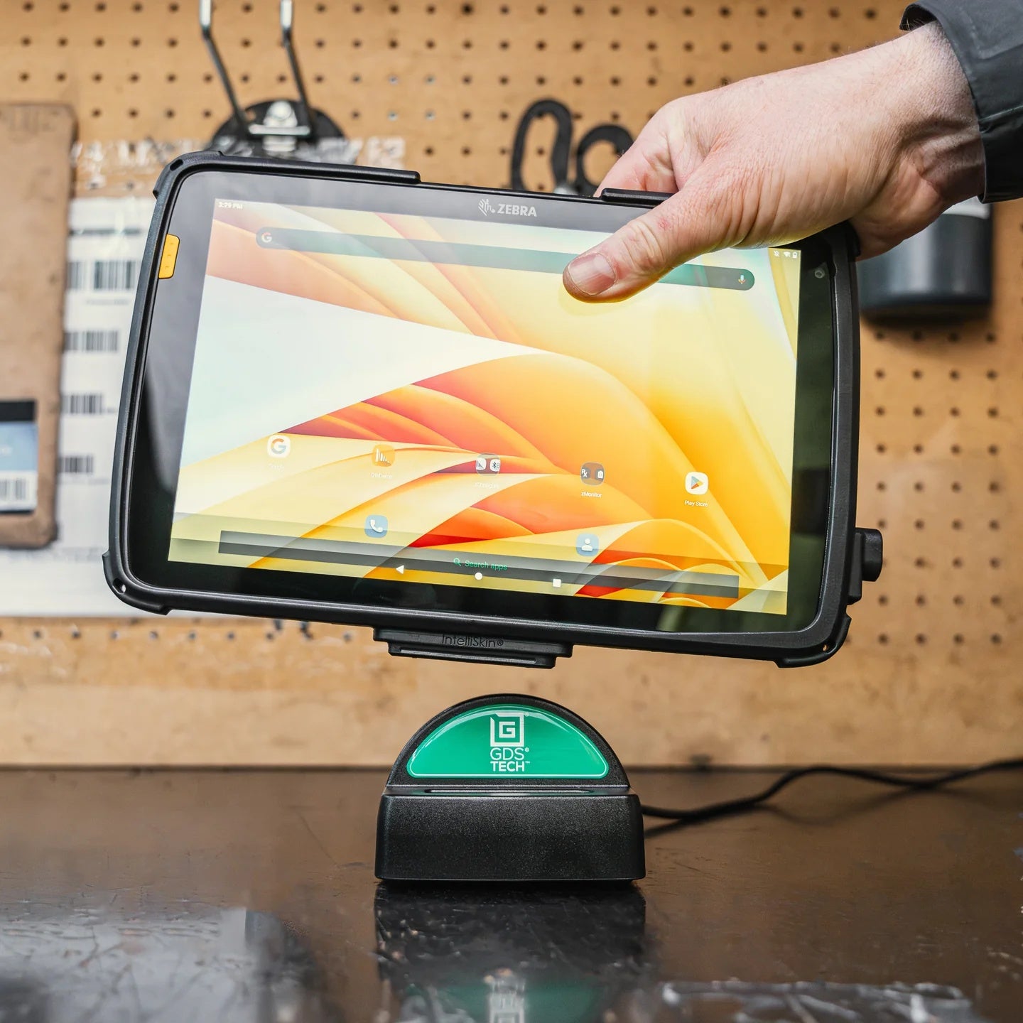 Hand holding a tablet with a screen displaying colorful graphics, placed on a charging dock with a visible GDS brand logo.